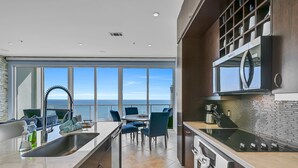 A modern kitchen with a large island, a dining area with a view of the ocean, and a built-in oven. - PH, Balcony, Lazy River, I-O Pools, Game Room, Spa, Beach, Luxury 2-2 Penthouse! (Galveston)