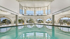 A large indoor swimming pool with multiple levels of seating and large arched windows. - PH, Balcony, Lazy River, I-O Pools, Game Room, Spa, Beach, Luxury 2-2 Penthouse! (Galveston)
