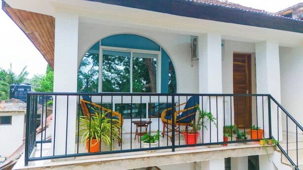 Un balcon avec une balustrade, des plantes en pot et une vue sur les arbres.