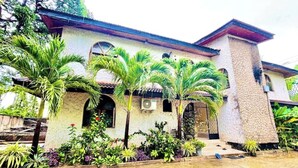 Une maison à deux étages, dotée d’une façade en pierre, de fenêtres en arc de cercle et d’un toit recouvert de tuiles.