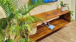 Un salon doté d’un téléviseur à écran plat fixé au mur, d’un meuble de rangement en bois en dessous et de plusieurs décorations murales tissées.