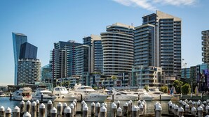 A marina with yachts docked, surrounded by modern high-rise buildings.
