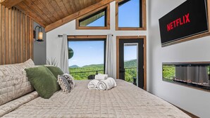 A bedroom with a large bed, a view of the outdoors, a Netflix sign, and a fireplace.