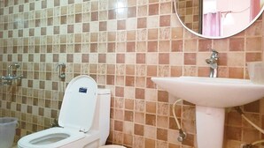 Une salle de bain avec des toilettes, un lavabo et des murs carrelés.