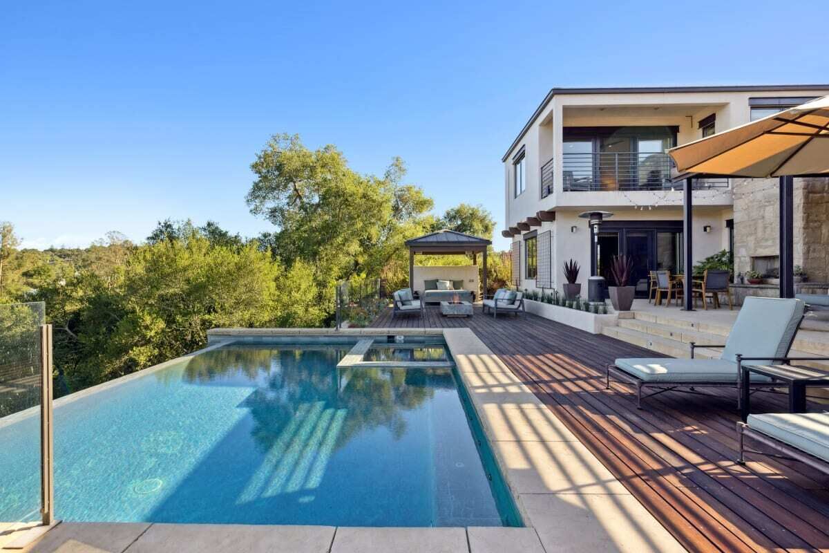 Una casa moderna con piscina, mobiliario exterior y terraza.