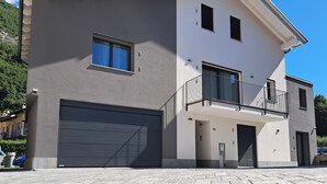 A two-story modern house with a garage, a balcony, and a small window. - Cozy lodging between the lake and the mountains (Morbegno)