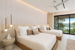 A modern hotel room with two beds, a large window with a view, a ceiling fan, and a nightstand with a lamp. - 6 BR Architectural Masterpiece in Peninsula Papagayo (Nacascolo)