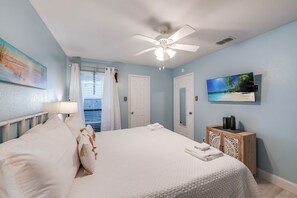 A bedroom with a bed, a ceiling fan, a TV, and a cabinet. - First-Floor Waterfront Condo | Pool, Hot Tub & Canal Views (Corpus Christi)