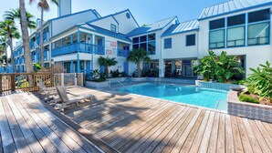 Un hôtel doté d’une piscine, d’une terrasse en bois et de balcons.