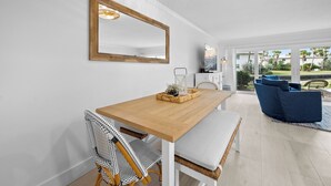 A dining area with a wooden table, white chairs, a large mirror, and a blue sofa in the background. - LBK Whitney Beach Retreat 1 (Longboat Key)