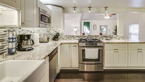 Una cocina con armarios blancos, estufa de acero inoxidable y salpicadero de azulejos.