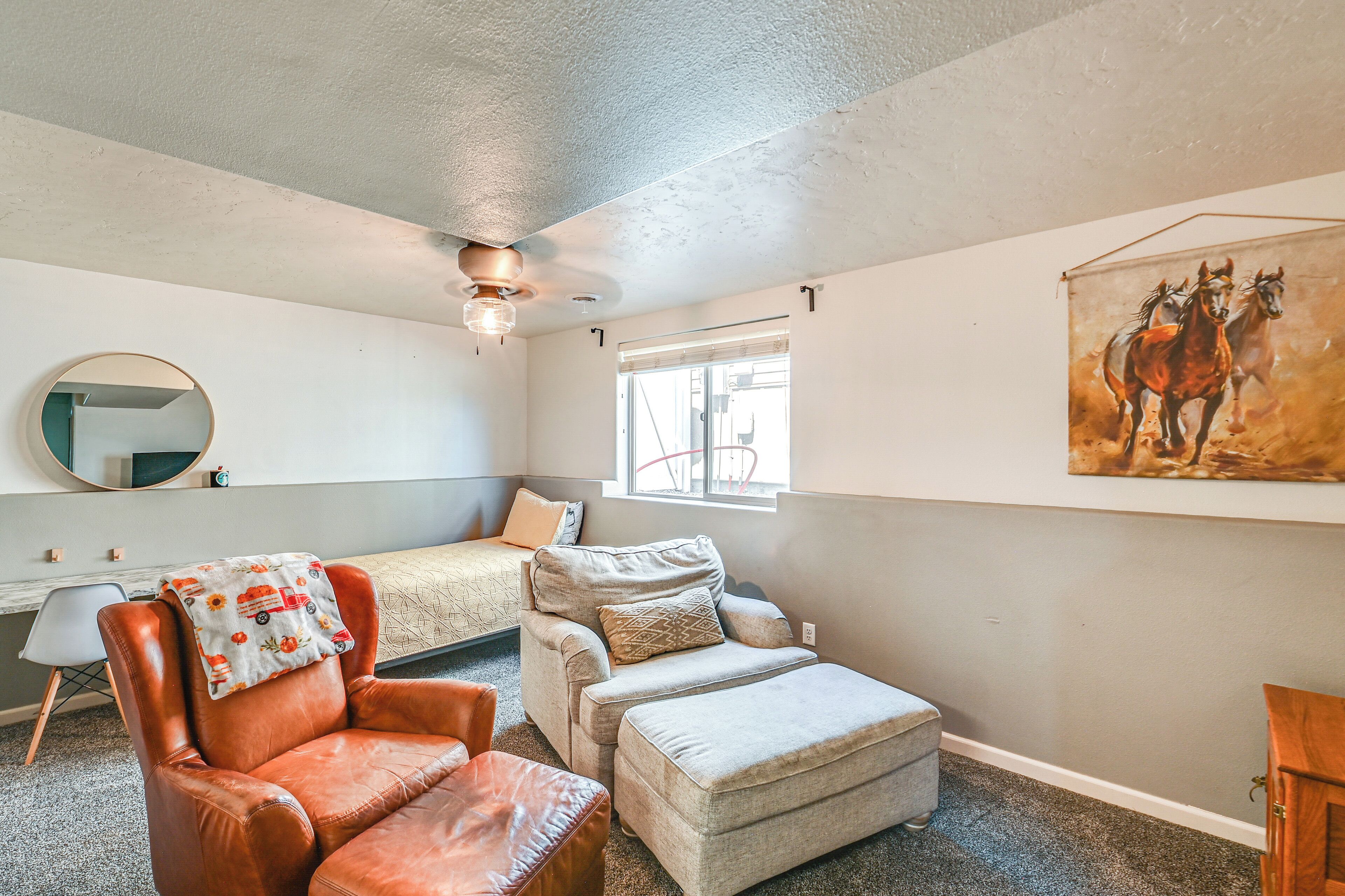 A bedroom with a bed, a chair, a small table, a mirror, and a painting on the wall.