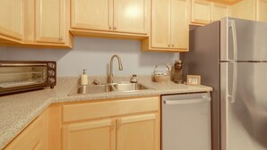 A kitchen with wooden cabinets, a stainless steel refrigerator, a dishwasher, a toaster, and a sink. - 1 Mi to Dtwn & Uga: Condo w/ Pool in Athens! (Athens)