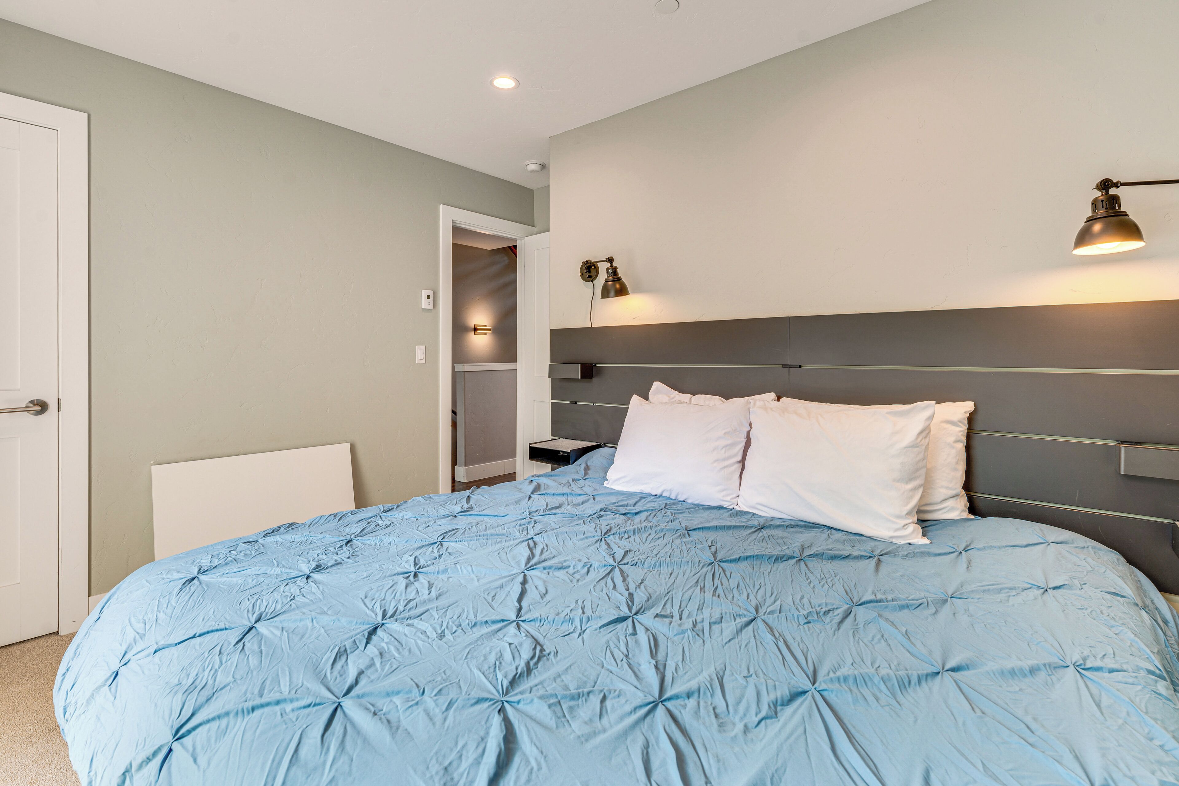 A bedroom with a large bed, a bedside table, a nightstand, a wardrobe, and a door.