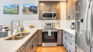 A kitchen with wooden cabinets, stainless steel appliances, and a white countertop. - Ski-in/ski-out Gemini Lift Access! Home w/ Hot Tub (Winter Park)