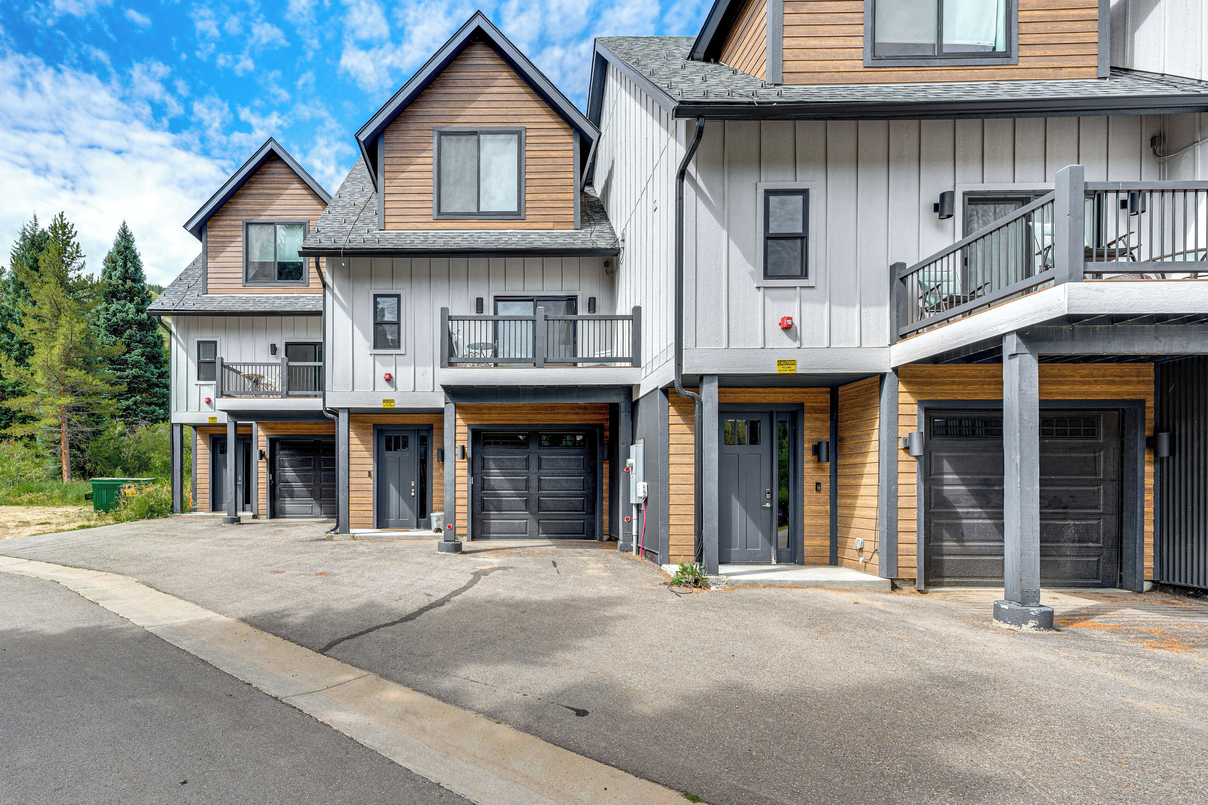 A row of modern townhouses with attached garages, wooden facades, and balconies.