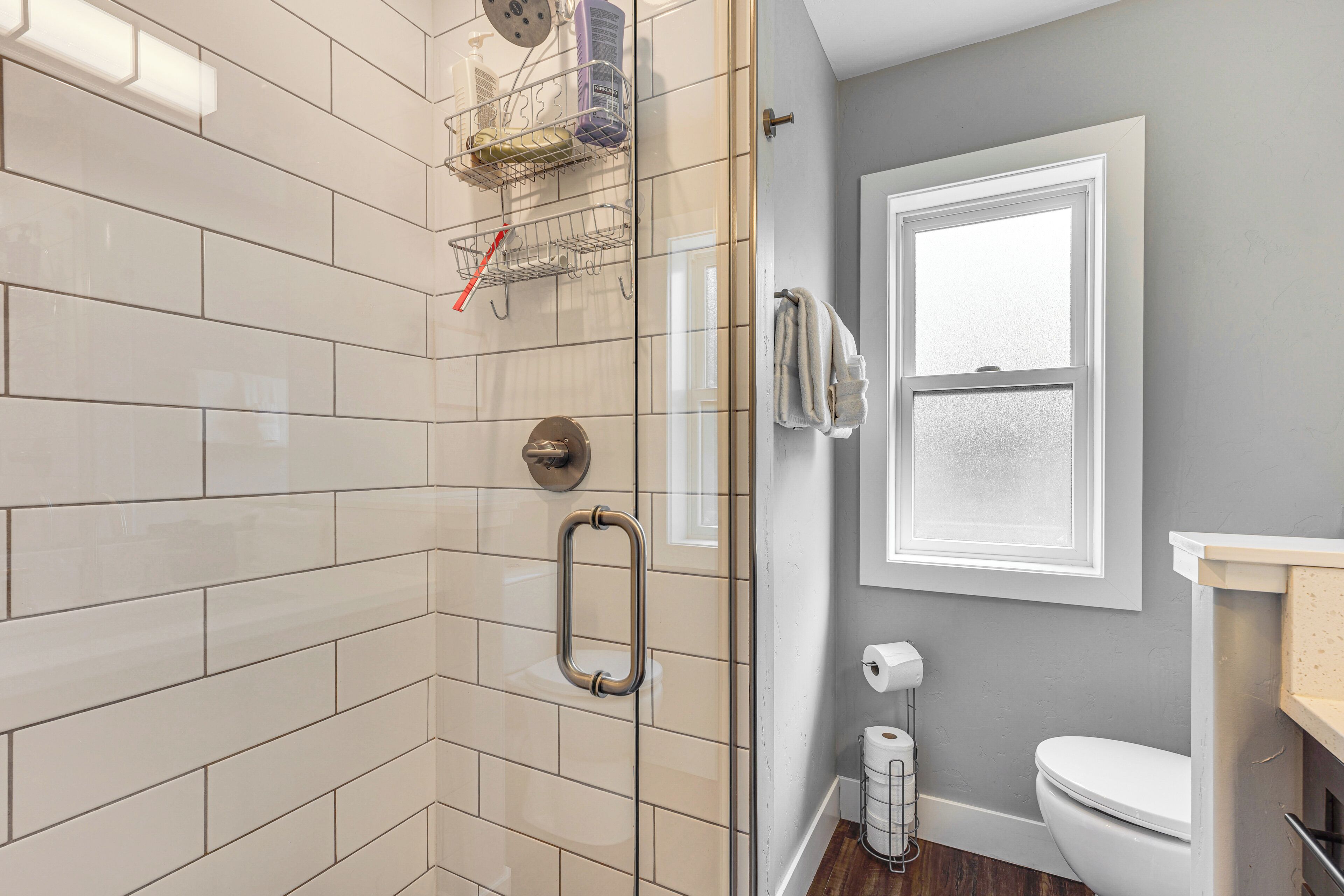 Un baño con cabina de ducha de vidrio, inodoro y zona de lavamanos.