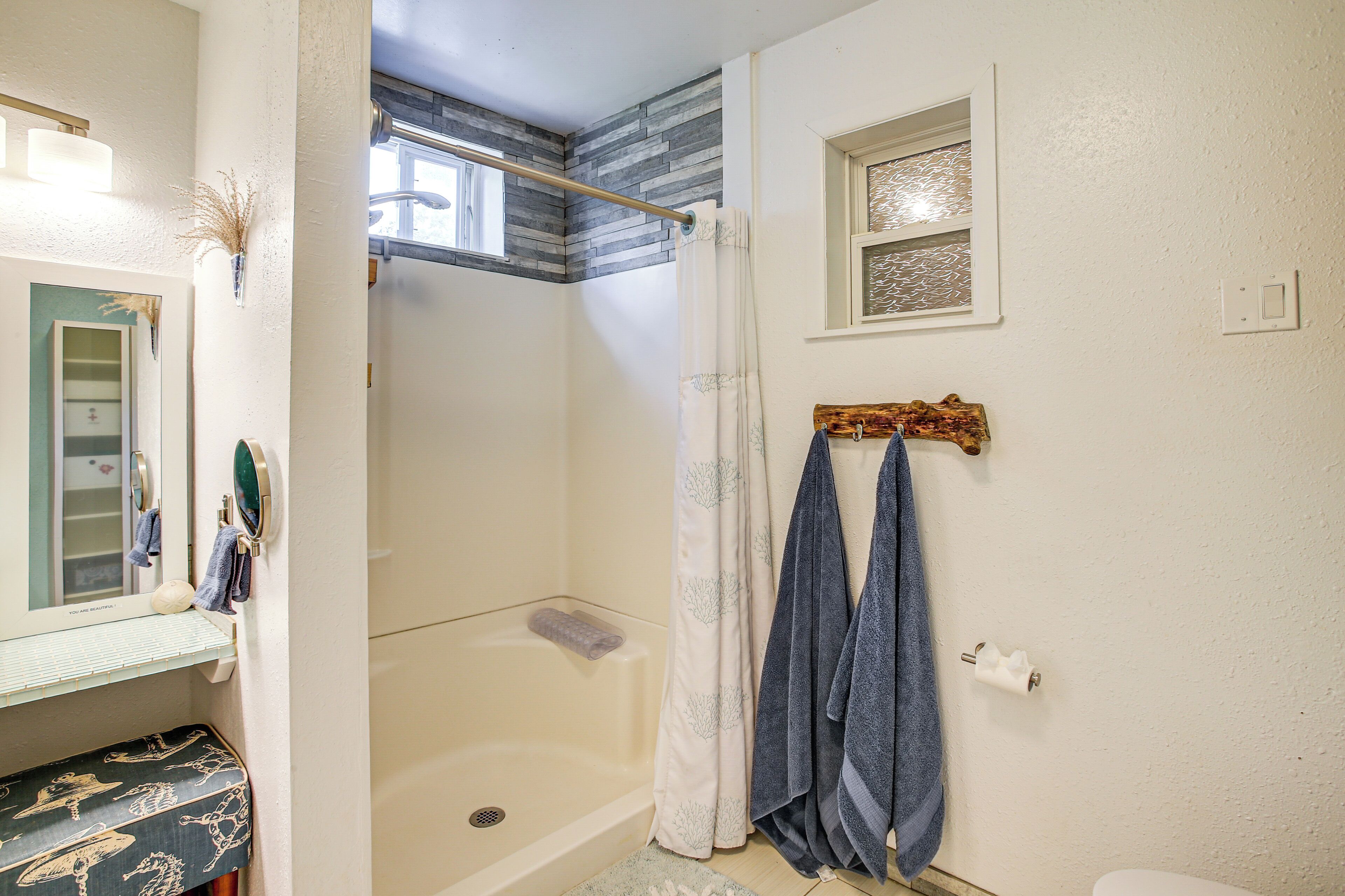 Een badkamer met een douche, toilet, wastafel met spiegel en een handdoekrek.
