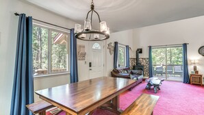 A spacious room with a large wooden table, benches, and a chandelier. - Hike, Swim, Golf: Family Retreat in Arnold! (Arnold)