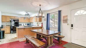 A kitchen with wooden cabinets, a black refrigerator, a wooden dining table with benches, and a chandelier. - Hike, Swim, Golf: Family Retreat in Arnold! (Arnold)