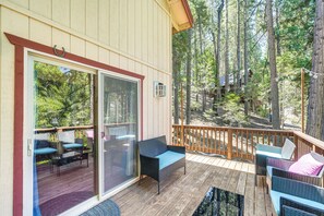 Une terrasse couverte, aménagée avec des meubles en osier et dotée d’une porte vitrée donnant sur un espace patio.