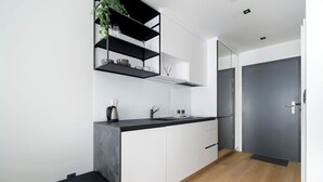 A modern kitchen with white cabinets, a black countertop, and a built-in shelf unit. - Modern Studio in the Center of Poznań | Smart TV (Poznań)
