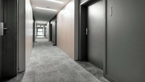 A modern hallway with carpeted floors, dark walls, and doors numbered 237. - Modern Studio in the Center of Poznań | Smart TV (Poznań)