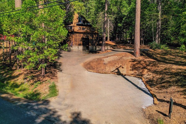 A forested area with a dirt path leading to a wooden cabin with a balcony. - Walk to Fly-in Lake: Blue Lake Springs Cabin! (Arnold)