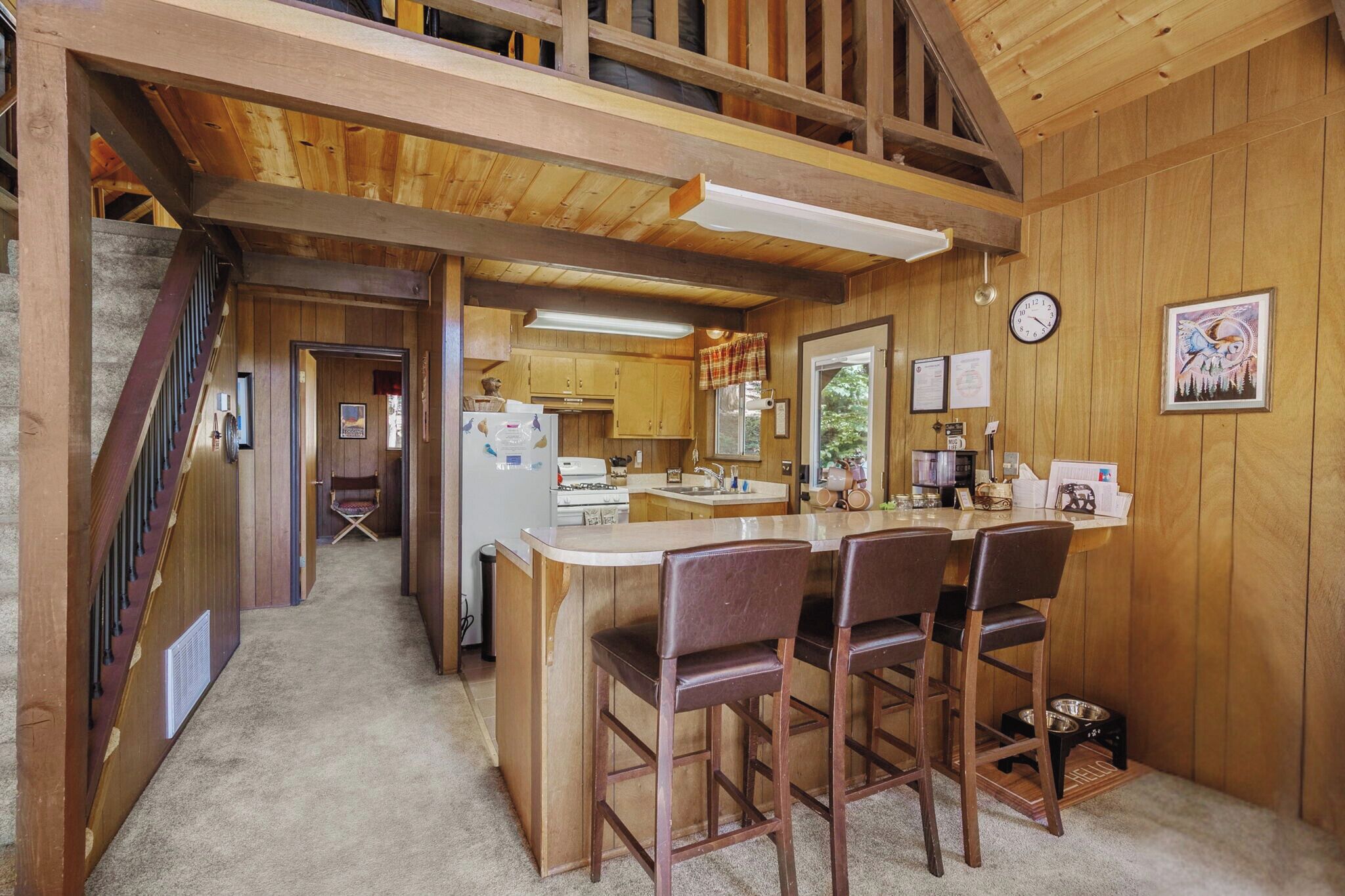 Ein Holzinterieur mit Küche, Essbereich und einer Treppe.