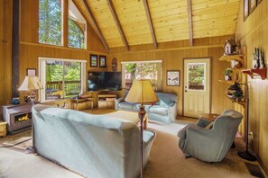 A cozy cabin interior with a fireplace, comfortable seating, and wooden walls. - Walk to Fly-in Lake: Blue Lake Springs Cabin! (Arnold)