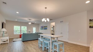 A spacious kitchen with a dining area, wooden flooring, and a modern chandelier. - 3 Mi to Sand & Surf: Ocean Isle Beach Retreat! (Ocean Isle Beach)