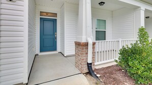 A white house with a blue door, a brick column, and a white porch railing. - 3 Mi to Sand & Surf: Ocean Isle Beach Retreat! (Ocean Isle Beach)
