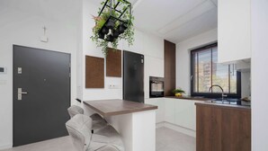 A modern kitchen with a central island, black appliances, and a hanging plant.