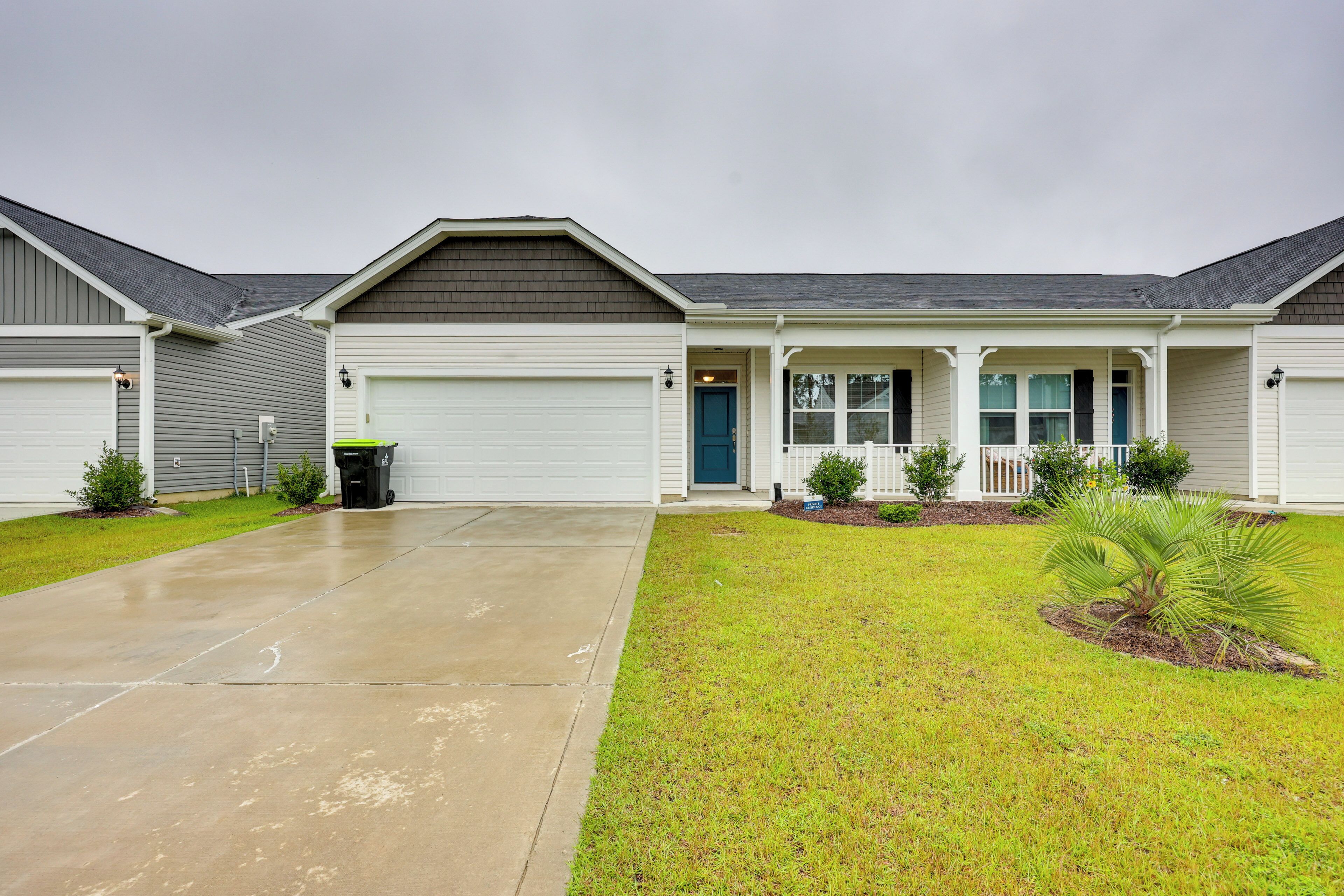 A residential building with a garage, a front porch, and a well-maintained lawn.