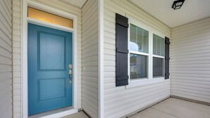 Ein Haus mit blauer Tür, weißem Putz und einem Fenster mit Fensterläden.