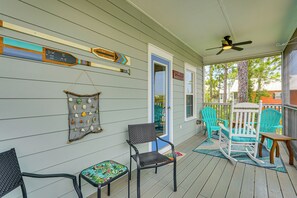 A covered porch with a ceiling fan, rocking chairs, and a wall adorned with decorative items. - Poolside Fun + Ocean Strolls: Port St Joe Retreat! (Port St. Joe)