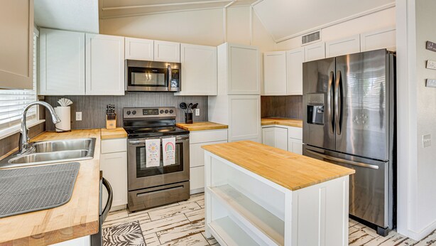 A modern kitchen with white cabinetry, stainless steel appliances, and a wooden countertop. - Welcoming Group Getaway w/ Pool & Patio in Peoria! (Peoria)