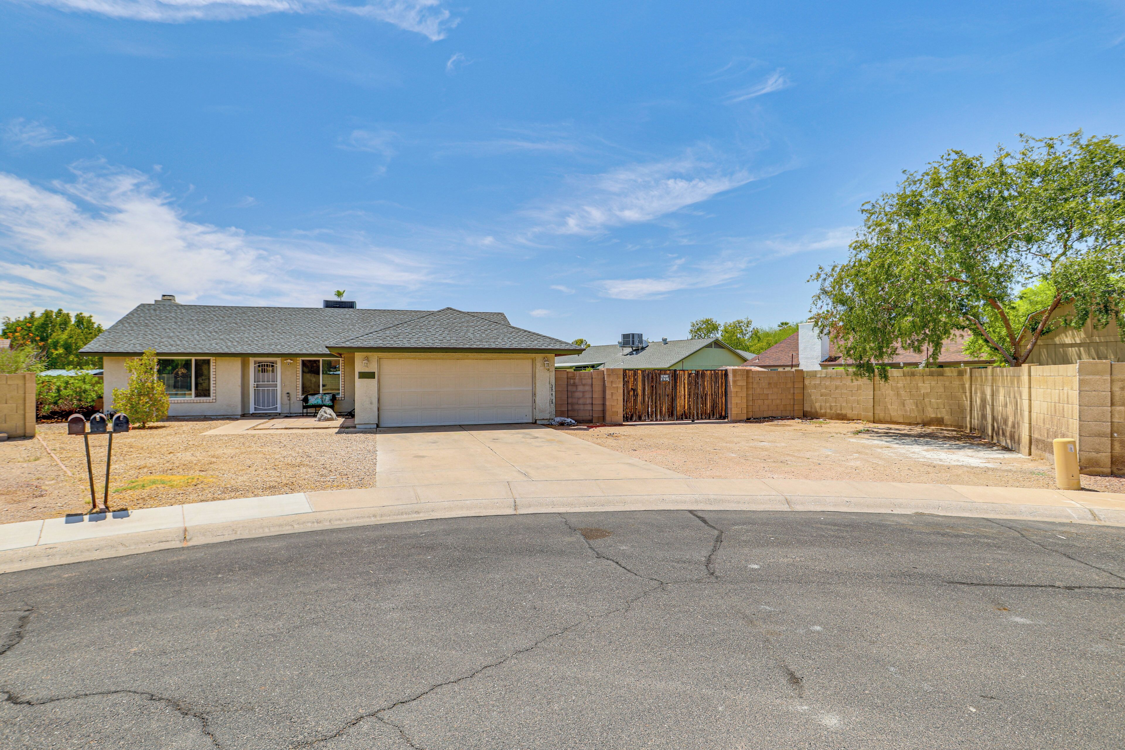 A residential property with a garage, a covered driveway, and a fenced yard.