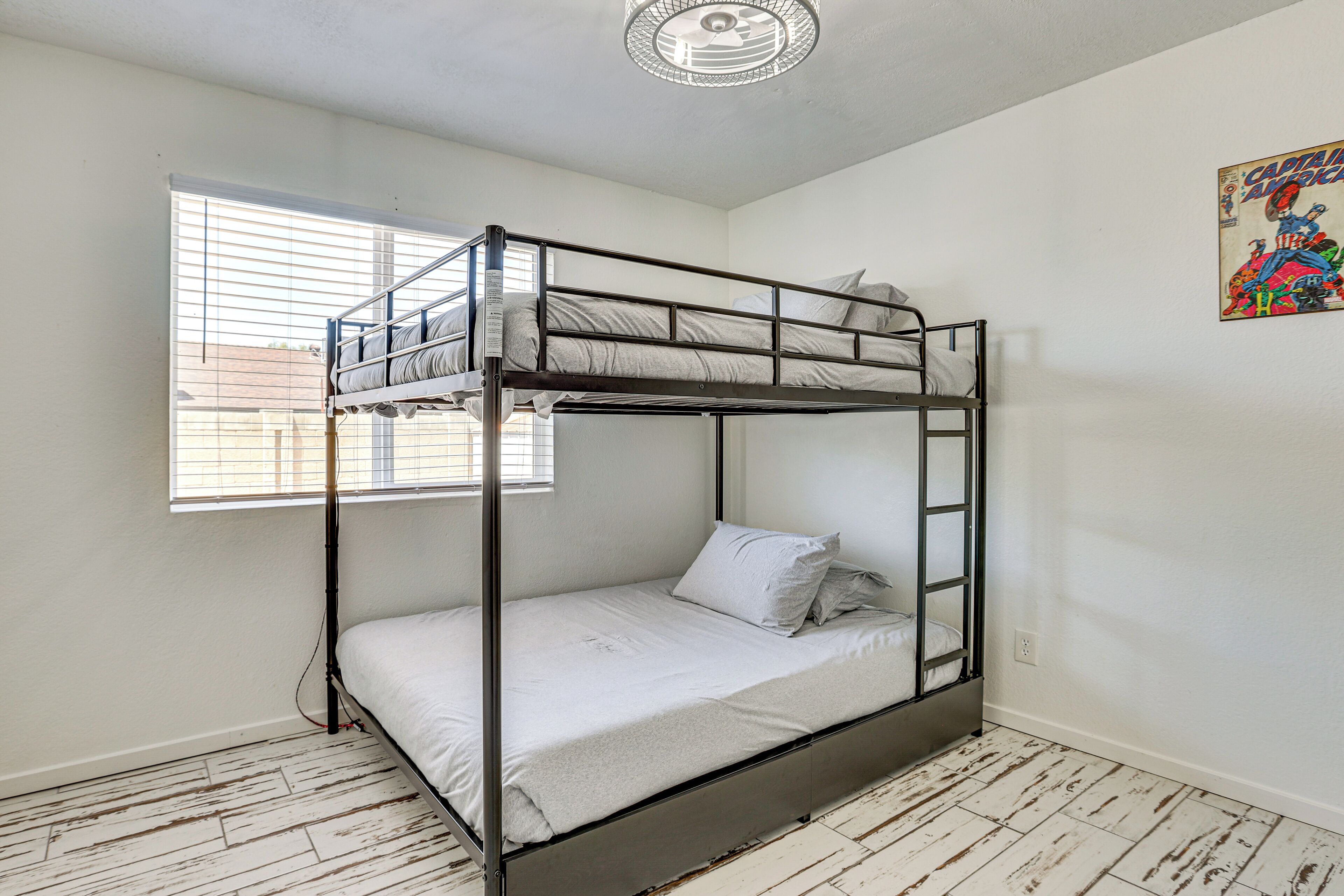 A bunk bed in a room with white walls, a window, and a ceiling fan.