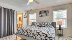 A bedroom with a bed, a ceiling fan, a window with blinds, and a nightstand with a lamp. - Welcoming Group Getaway w/ Pool & Patio in Peoria! (Peoria)