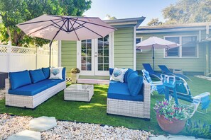 A patio area with two wicker sofas, a coffee table, and outdoor furniture under umbrellas. - St Pete Home for Retreat & Corporate Travelers (St. Petersburg)