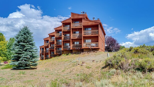 A multi-story wooden building with balconies, surrounded by natural vegetation and a clear sky. - Walk to Angel Fire Resort: Getaway w/ Balcony (Angel Fire)