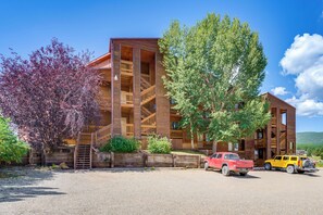 A lodge with a wooden exterior, multiple balconies, and a gravel driveway with parked vehicles. - Walk to Angel Fire Resort: Getaway w/ Balcony (Angel Fire)