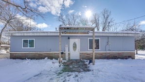 A single-story building with a covered entrance, a brick foundation, and a white door with a welcome sign. - Pet-friendly Retreat: Over 3 Acres in Baldwin! (Baldwin)