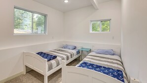 A bedroom with two single beds, a small table, and two windows. - Pet-friendly Retreat: Over 3 Acres in Baldwin! (Baldwin)