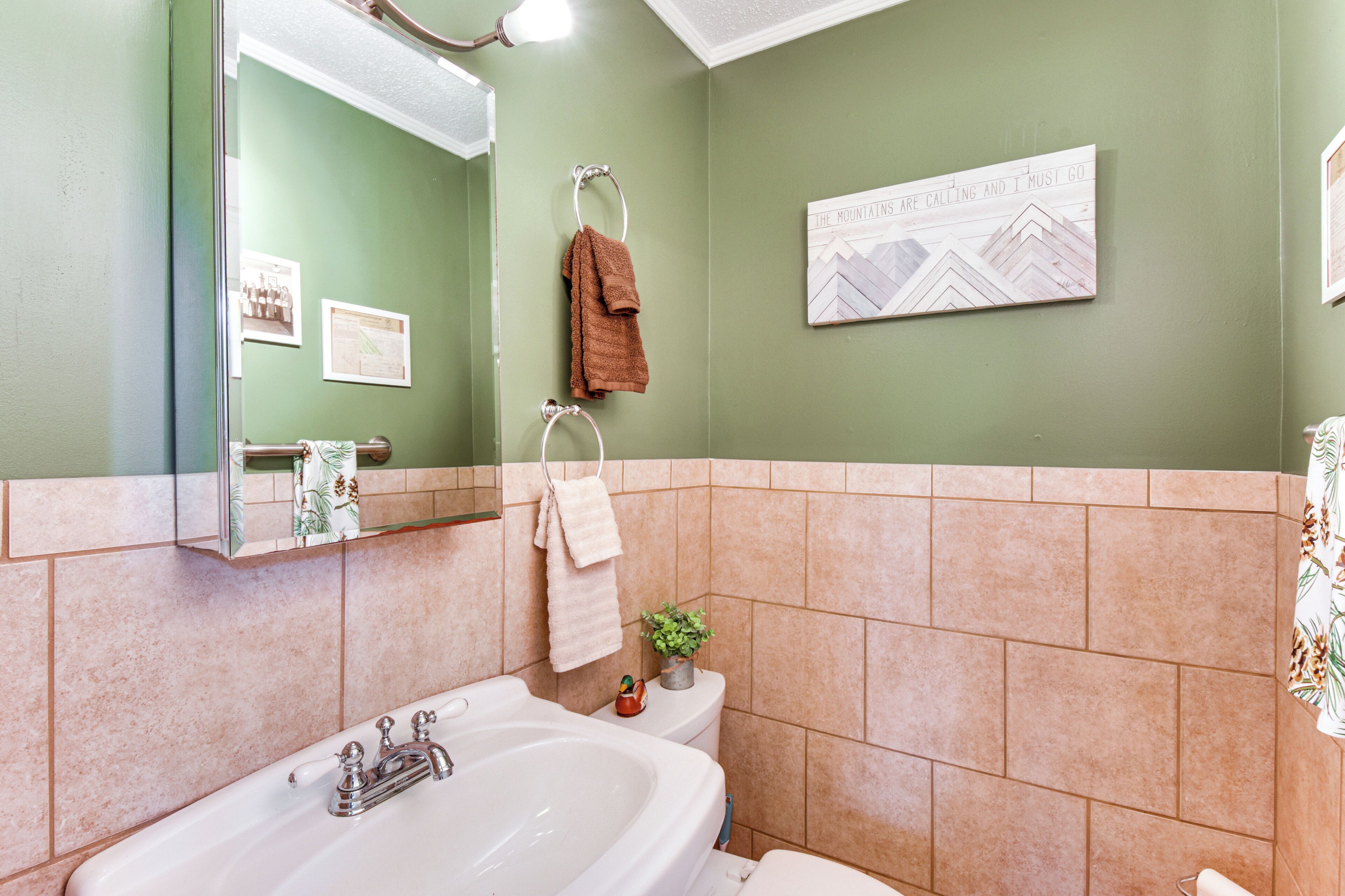A bathroom with a bathtub, a toilet, and a sink. There is a towel rack with towels and a framed picture on the wall.