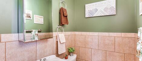 A bathroom with a bathtub, a toilet, and a sink. There is a towel rack with towels and a framed picture on the wall.