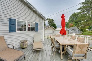 A wooden deck with a table and chairs, a red umbrella, and a white railing. - Fall Hikes & ORV Trails: Cozy Mears Retreat (Mears)