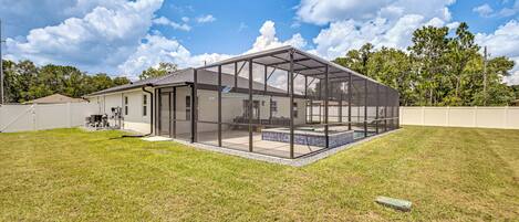 Et moderne hus med en stor glasfacade, swimmingpool og en velplejet græsplæne.