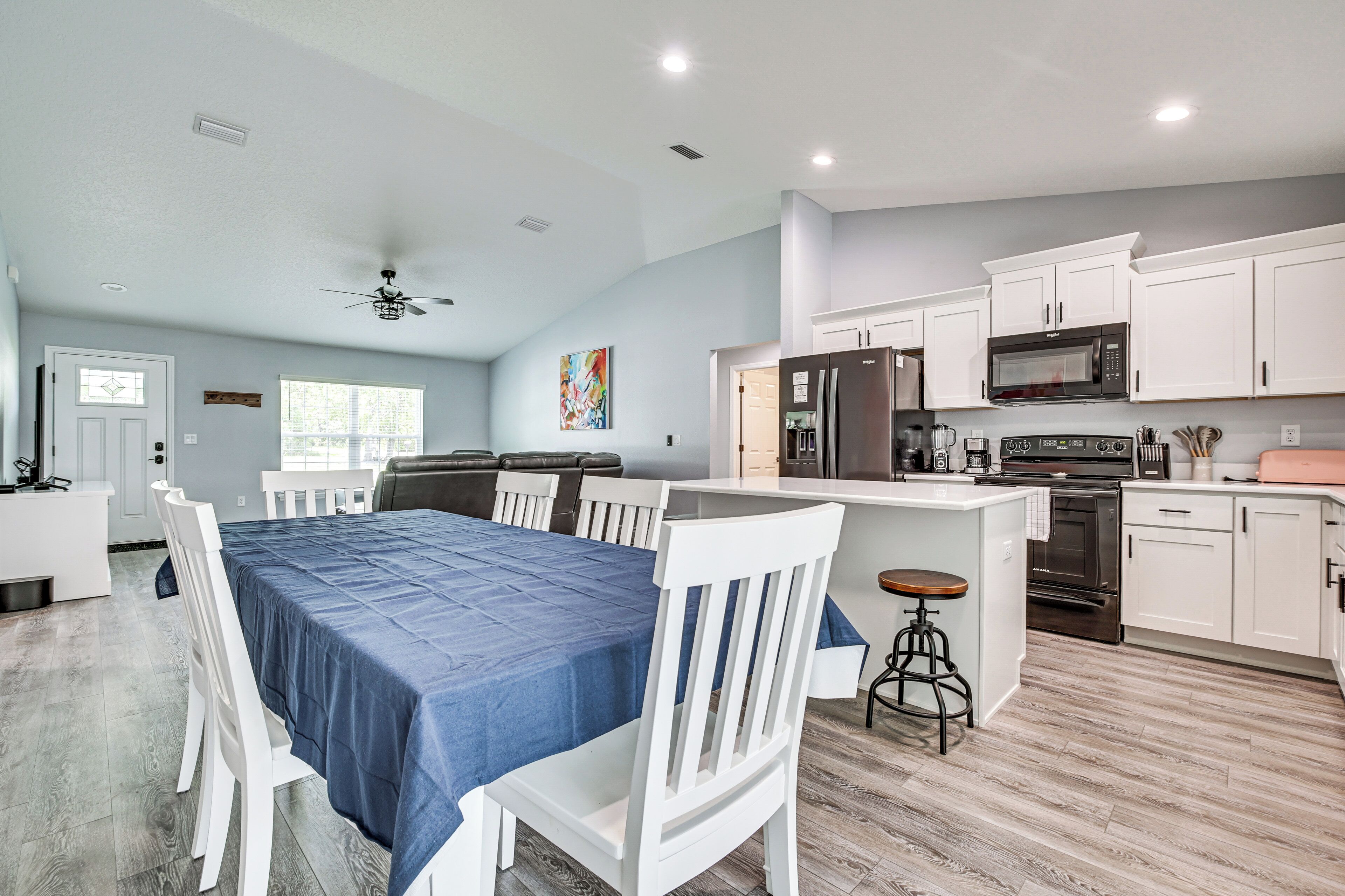 A modern kitchen with white cabinets, a stainless steel refrigerator, and a microwave.